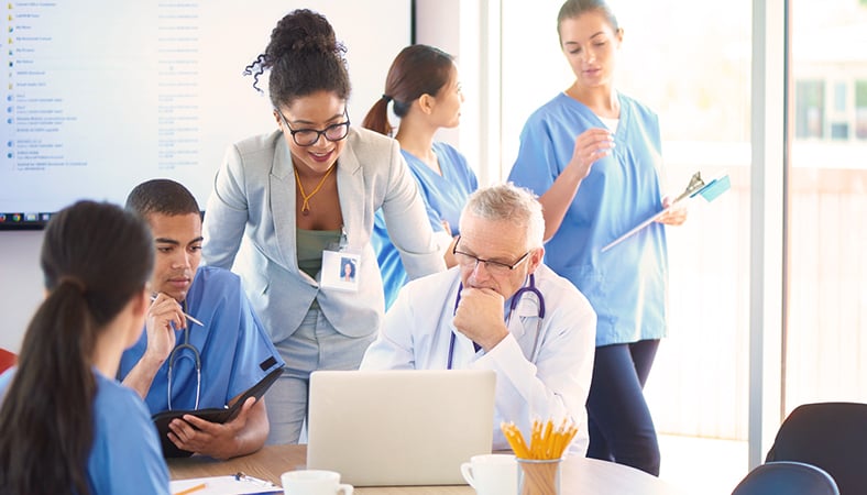 Mixed group of healthcare workers working on a laptop.